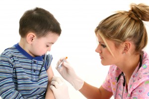 Small boy watching as nurse gives him a shot.