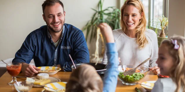Happy family enjoying lunch while kids playing.