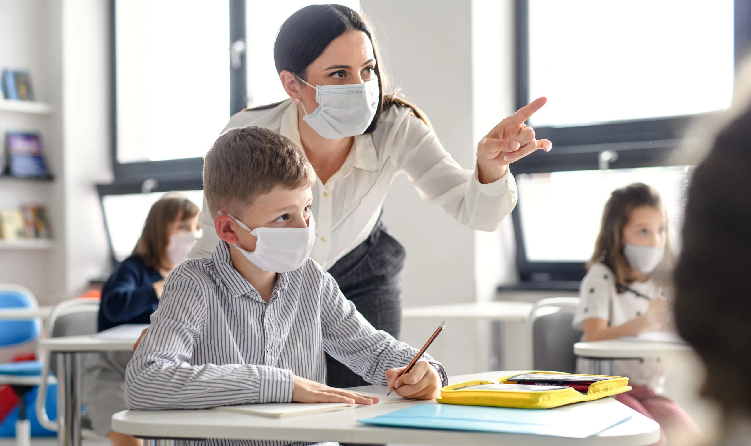 Teacher and children with face mask back at school after covid-19 quarantine and lockdown.